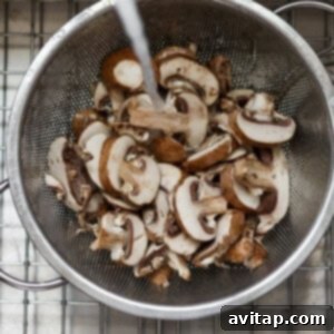 The Mushroom Swiss Burger 12 Cleaned and prepared Bella mushrooms resting in a strainer on a cooling rack, ready for cooking.