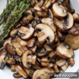 The Mushroom Swiss Burger 14 Perfectly sautéed mushrooms neatly arranged in a white bowl, garnished with a fresh sprig of thyme for presentation.
