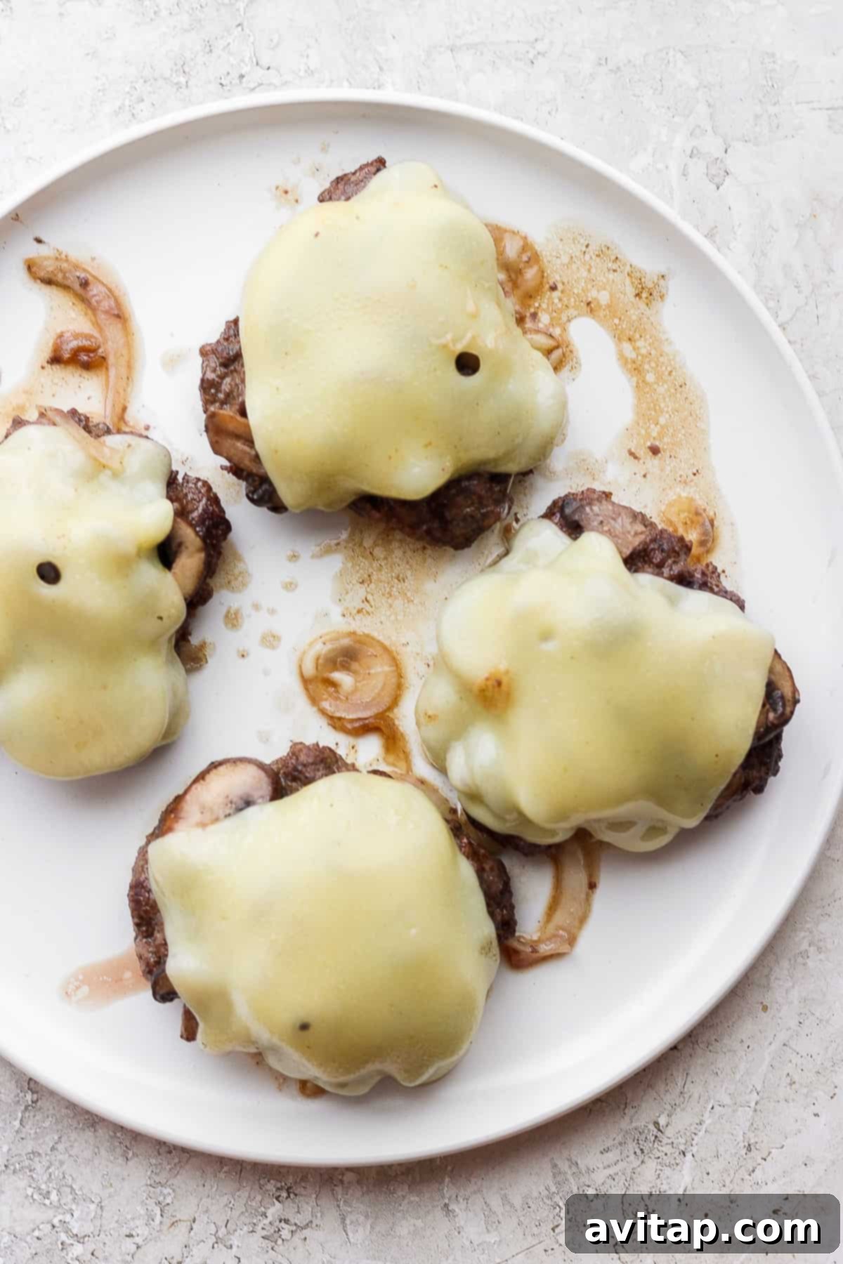 Savory Mushroom Swiss Burger 7 Four beautifully assembled mushroom Swiss burgers with pickles on a wooden cutting board.