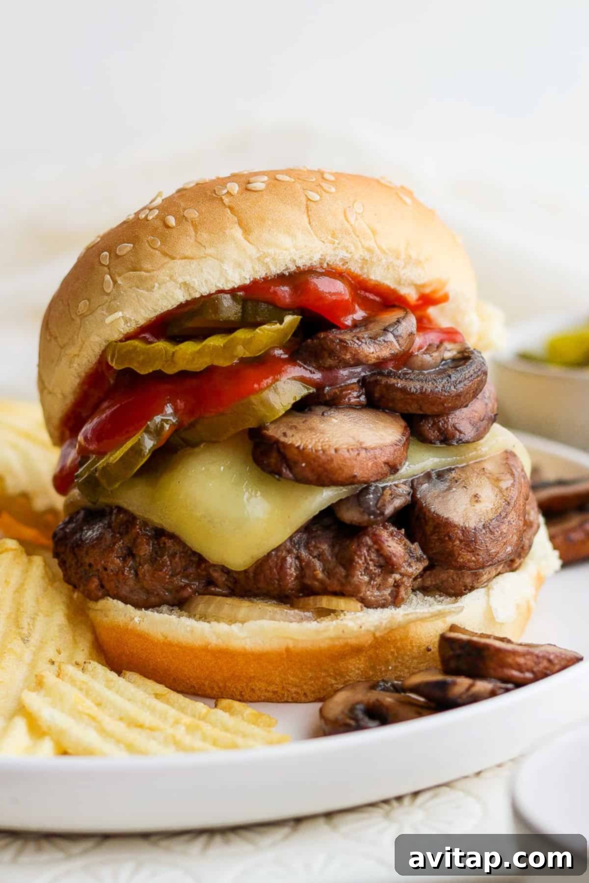 A mouthwatering mushroom Swiss burger on a plate, garnished with fresh greens and a side of sauce.