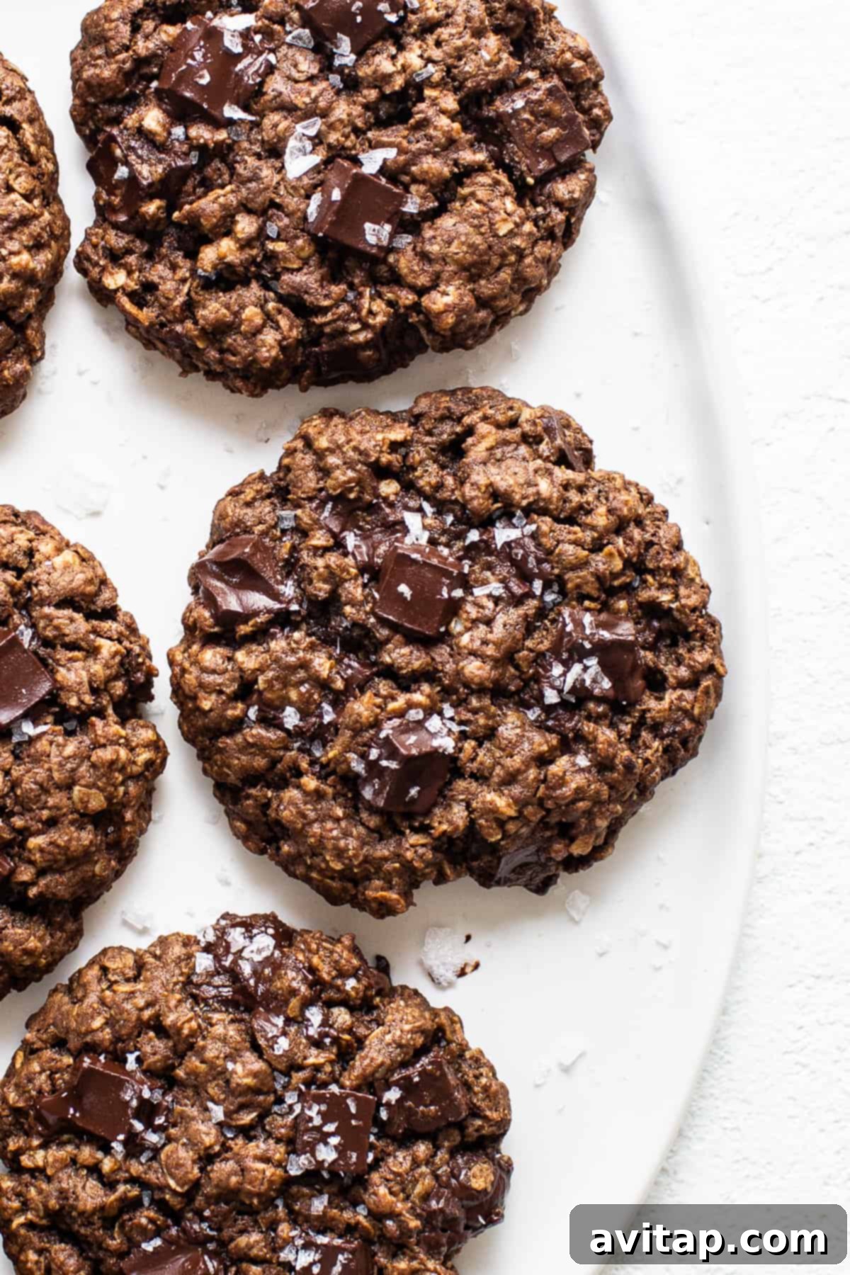 Close-up of freshly baked chocolate peanut butter oatmeal cookies on a white plate, showcasing their chewy texture and melted chocolate chunks.