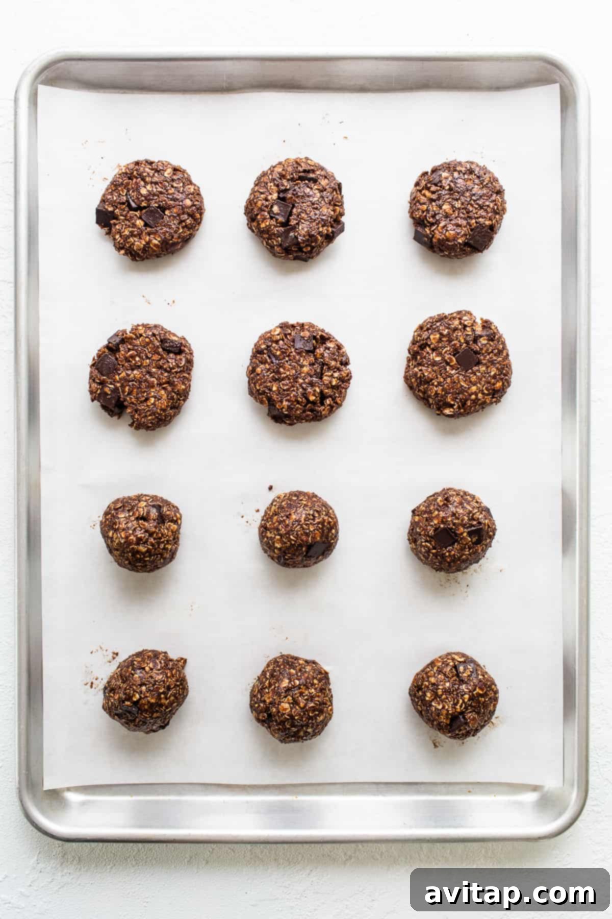 Freshly baked chocolate peanut butter oatmeal cookies cooling on a baking sheet, showing their characteristic slightly cracked tops and perfect golden edges.