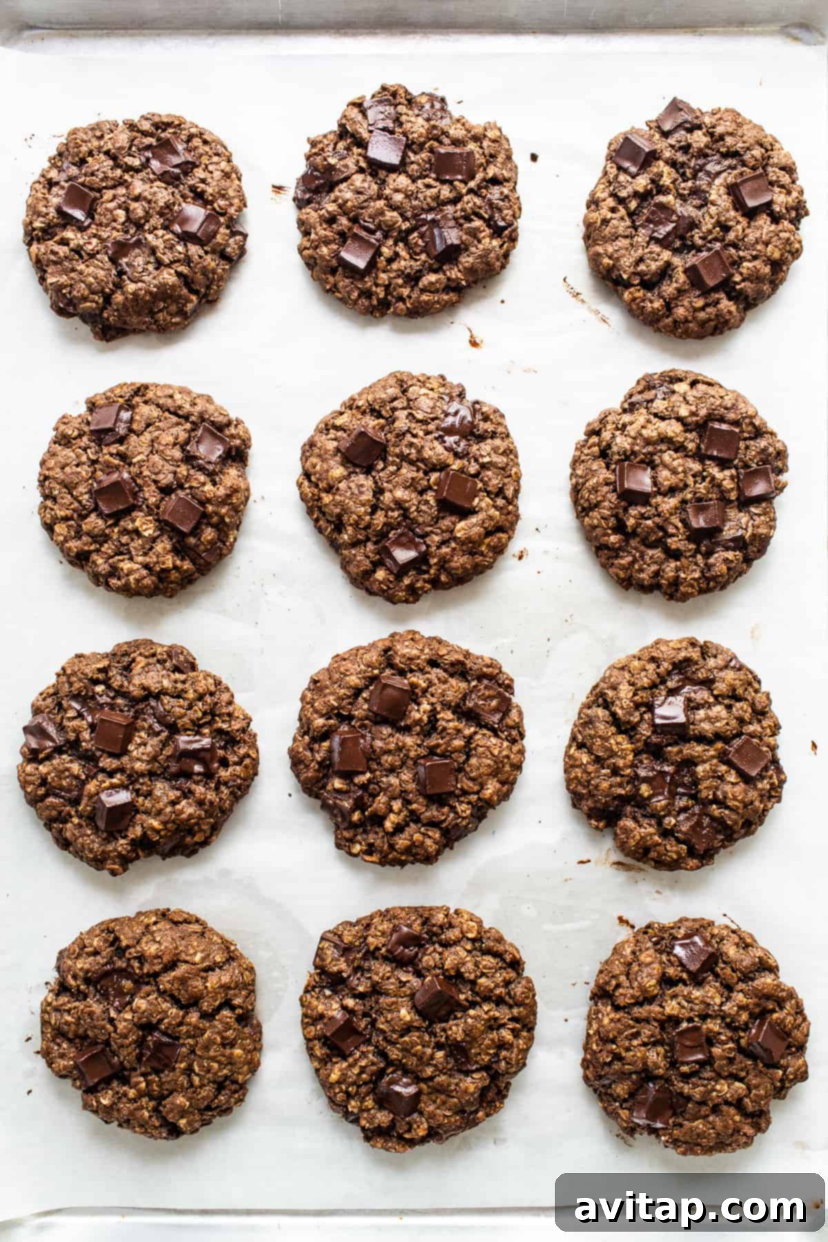 A baking sheet filled with freshly baked chocolate peanut butter oatmeal cookies, still warm and inviting, ready to be removed from the oven.