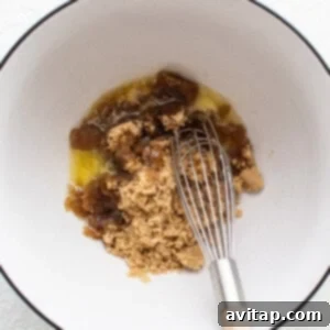 A bowl with a whisk and brown sugar in it, illustrating the mixing of wet ingredients for the cookie dough.