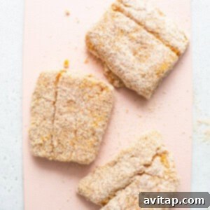 Three breaded cod pieces on a pink cutting board, ready for the air fryer.