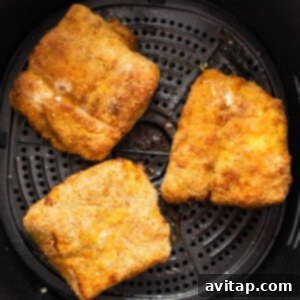 Crispy air fryer fish cooking inside an air fryer basket, showing golden-brown perfection.