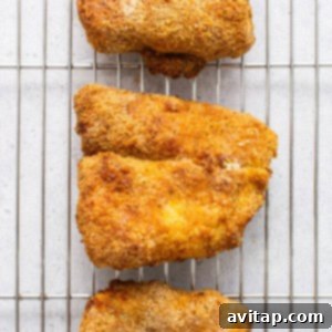Freshly cooked crispy air fryer fish resting on a cooling rack after cooking.