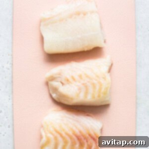 Raw cod fillets on a cutting board, ready for preparation.