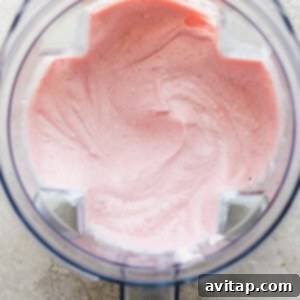 Pink whipped cream in a food processor, a step in making strawberry shortcake bars.