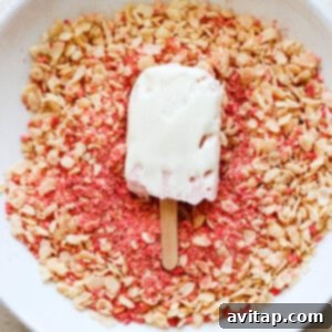 A high-protein strawberry shortcake bar being coated with granola.