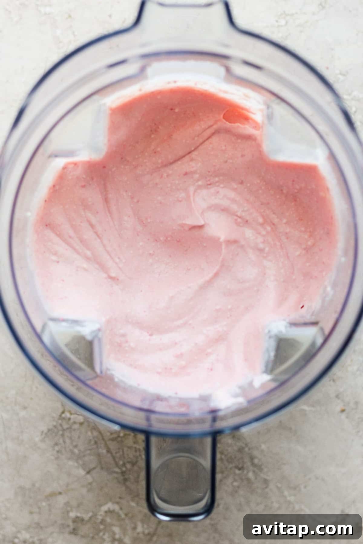 Smooth pink cottage cheese mixture in a food processor, ready for freezing.