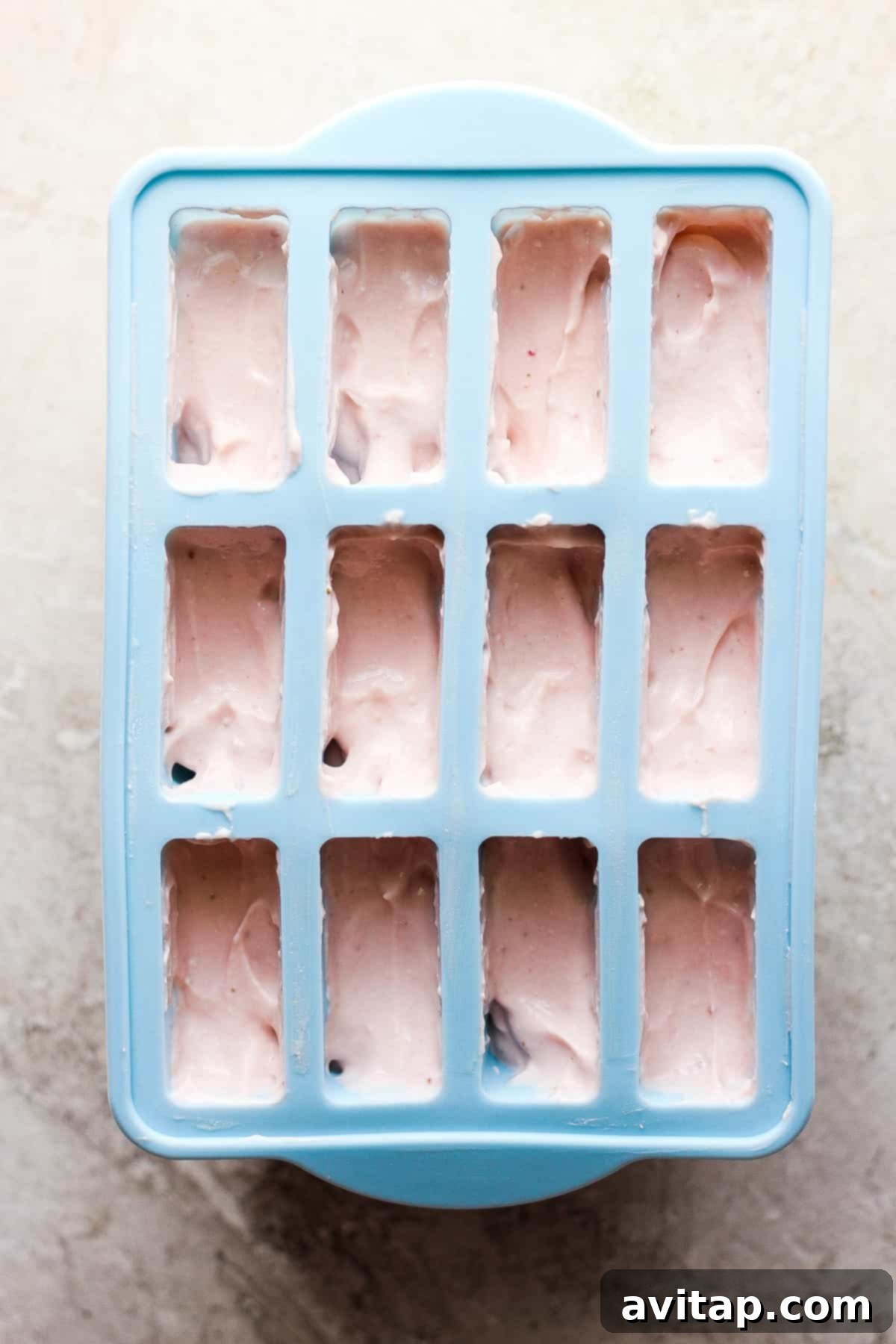 Frozen pink cottage cheese mixture in a blue silicone popsicle mold.