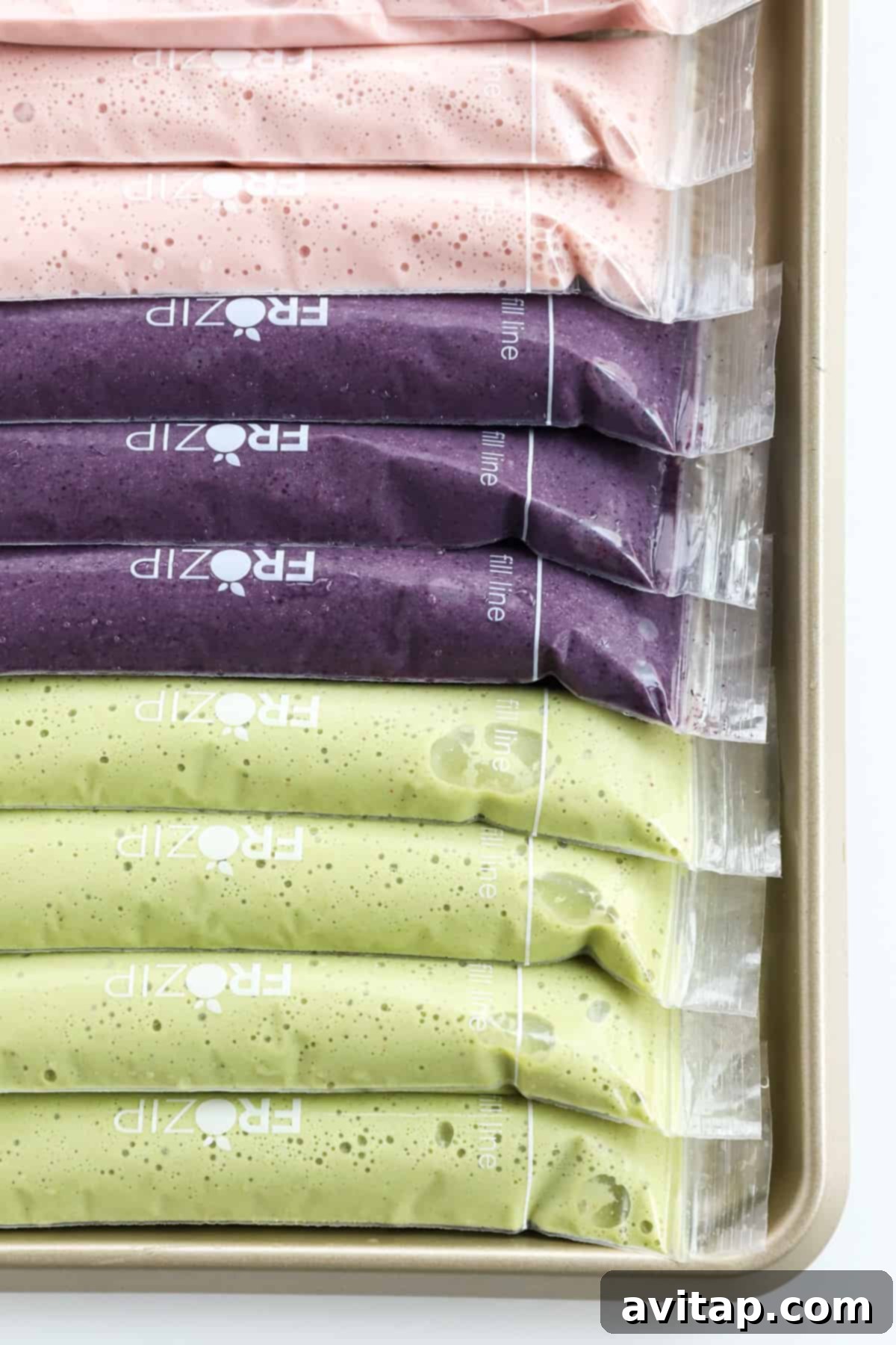 A tray filled with a variety of different colored smoothie popsicles, showcasing diverse flavors.