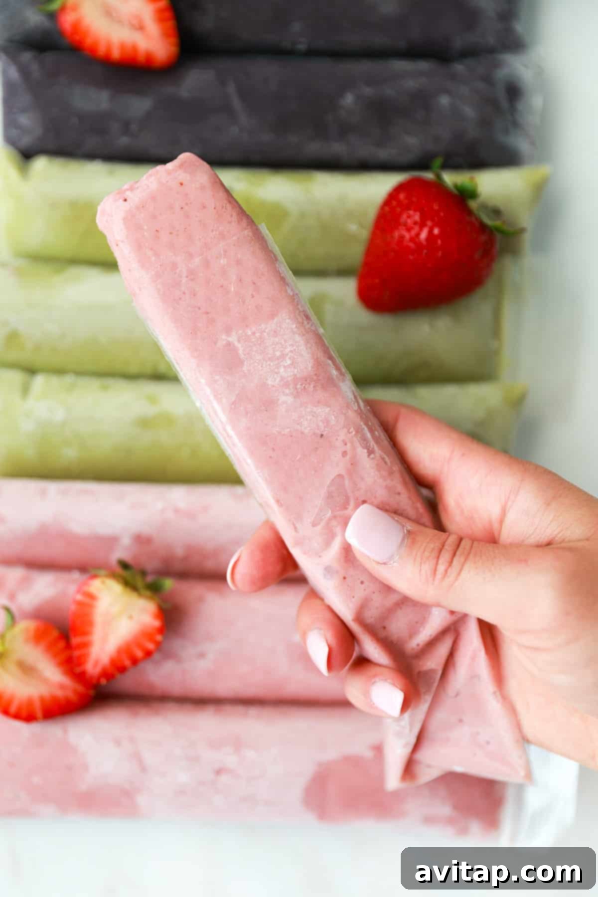 A hand holding a perfectly frozen smoothie popsicle, ready to be enjoyed.