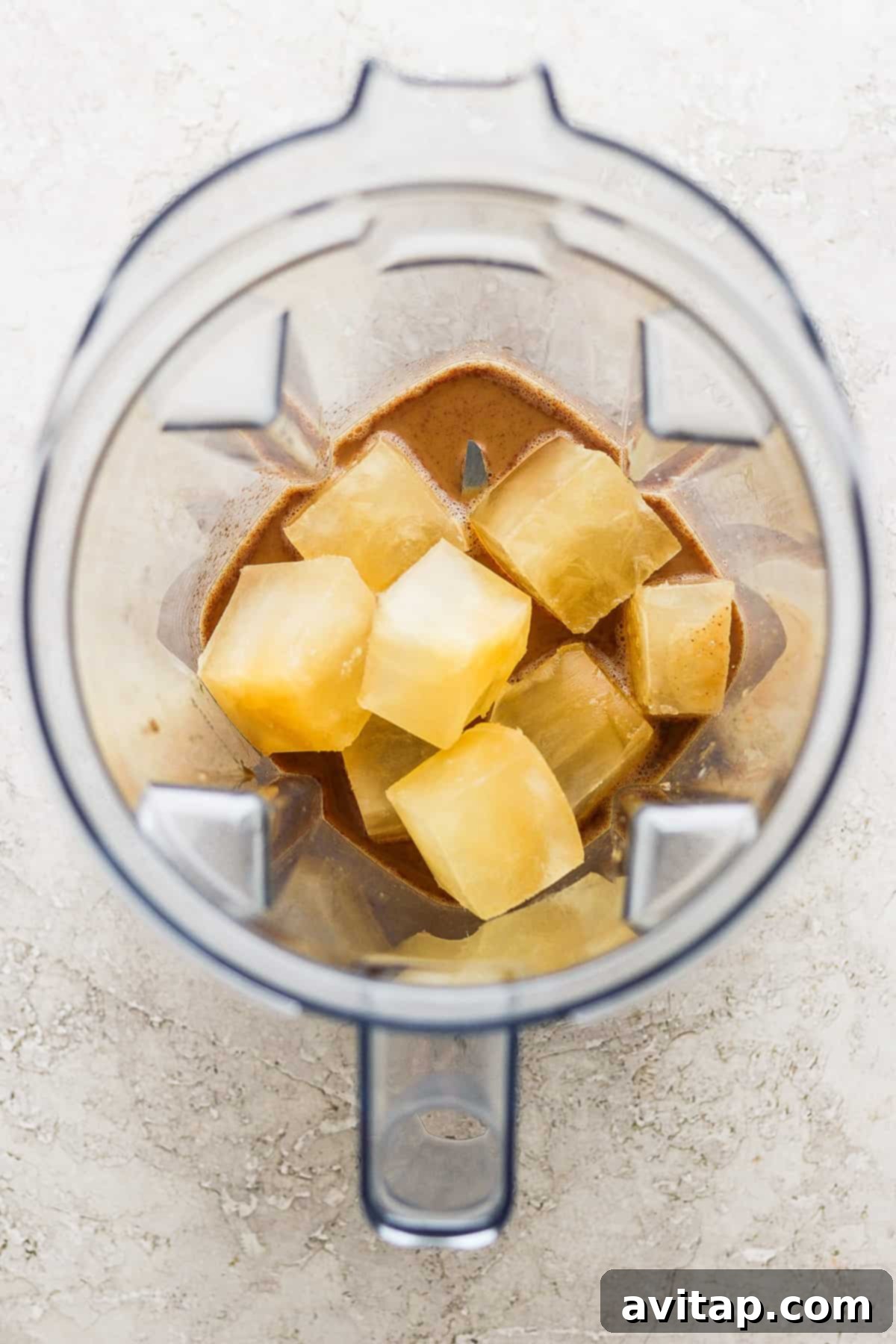 A powerful blender with fresh pineapple chunks being blended into a smoothie.