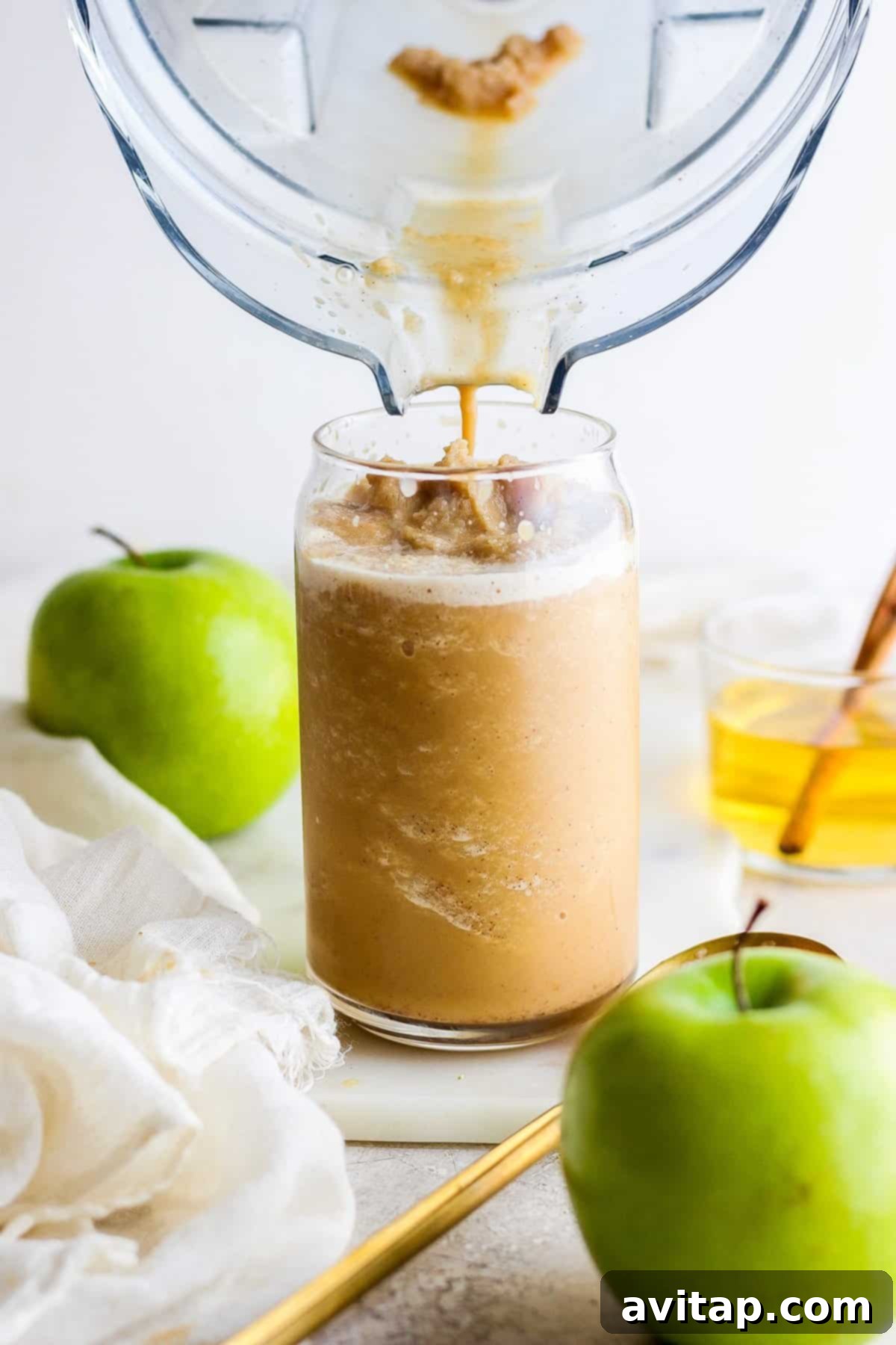Apple juice being poured into a clear glass, highlighting its golden hue.