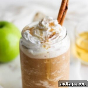 A mug with whipped cream and a cinnamon stick, representing the Apple Crisp Oatmilk Frappuccino.