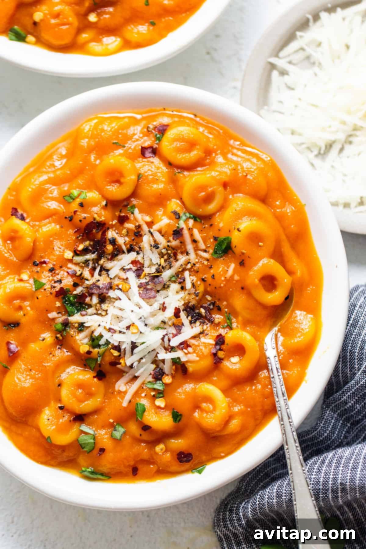 One-Pot Hidden Veggie O's 2 Two cozy bowls filled with vibrant orange pasta and a generous sprinkle of Parmesan cheese on a rustic wooden table, inviting a warm and comforting meal.