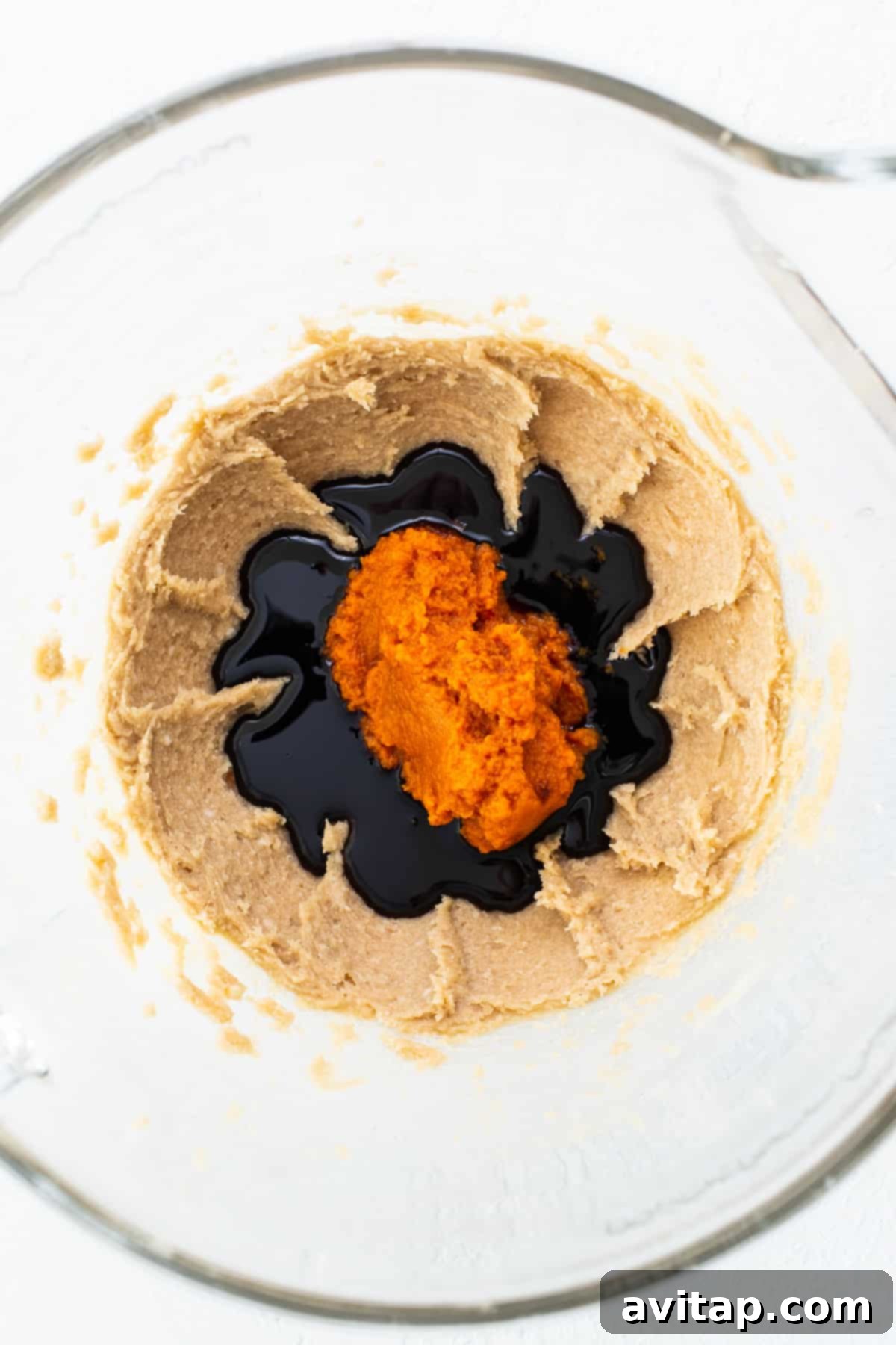 Warm Spiced Pumpkin Ginger Molasses Cookies 3 A glass bowl filled with a creamy, orange-hued mixture, ready for the next steps of cookie dough preparation.