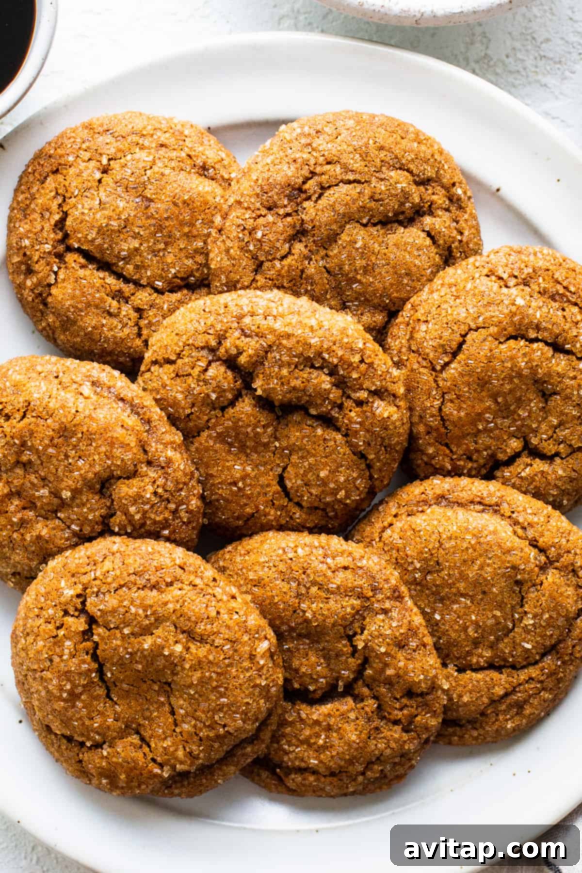 Warm Spiced Pumpkin Ginger Molasses Cookies 7 Ginger cookies arranged on a white plate next to a steaming cup of coffee, creating a cozy autumn scene.