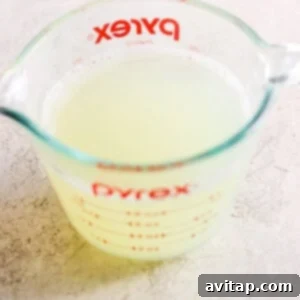 A glass measuring cup filled with starchy pasta water, essential for creamy sauces.