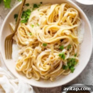 A delectable bowl of Cottage Cheese Alfredo pasta, elegantly garnished with fresh parsley and grated parmesan cheese.