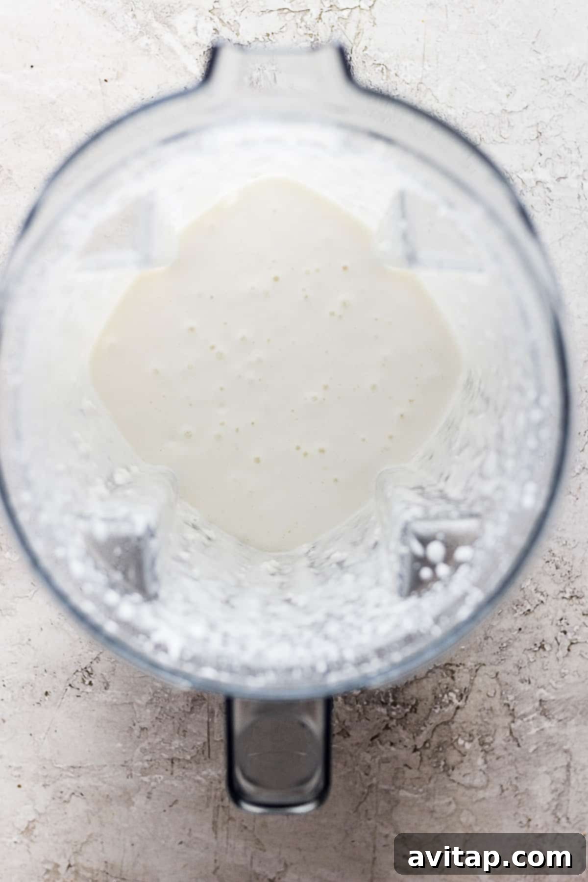 Creamy Cottage Cheese Alfredo 5 A high-speed blender actively blending white liquid, transforming cottage cheese into a smooth Alfredo sauce.