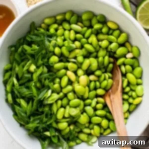 a white bowl filled with green beans and a wooden spoon.