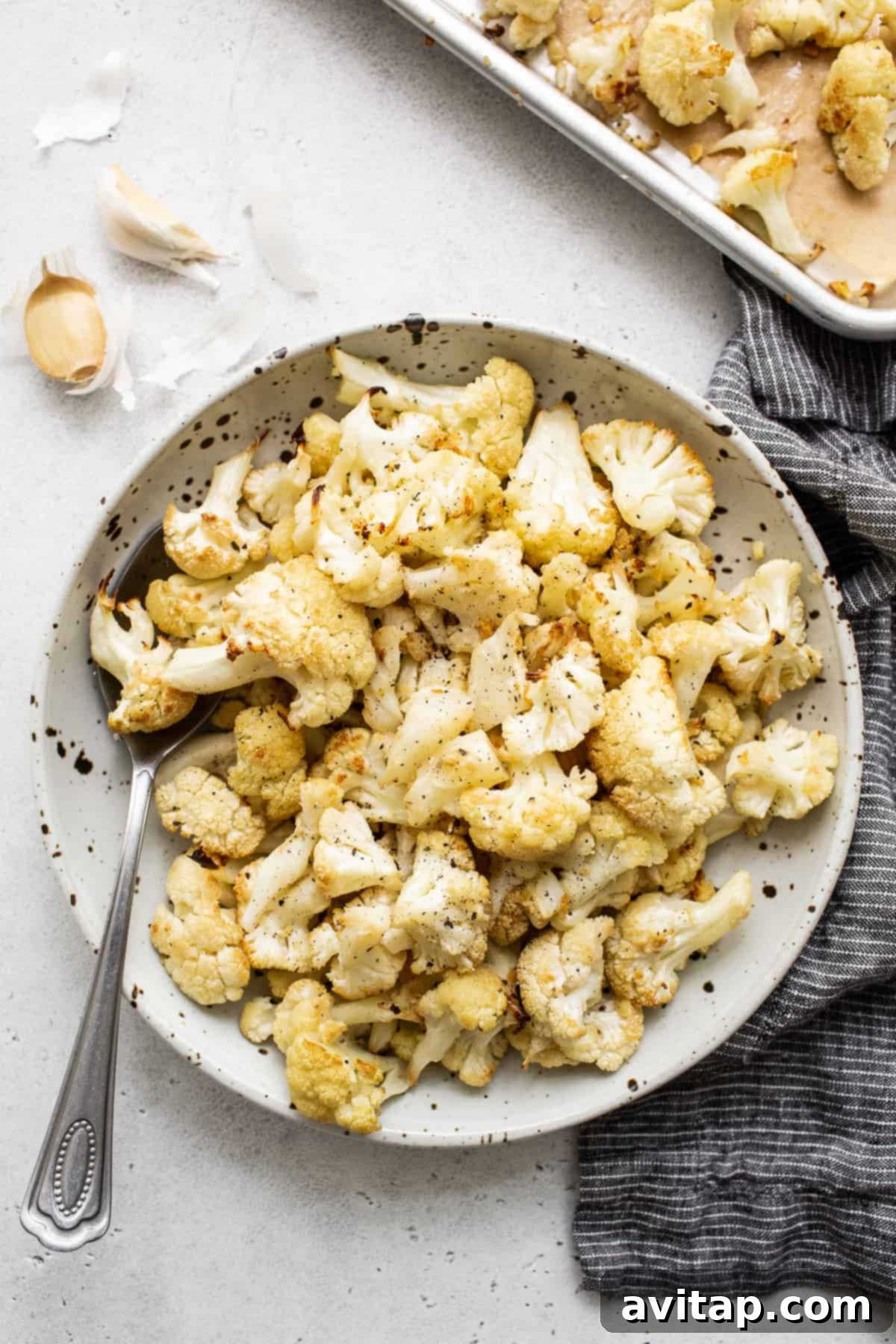 Garlic roasted cauliflower served in a rustic bowl, showcasing golden-brown florets with visible garlic bits.