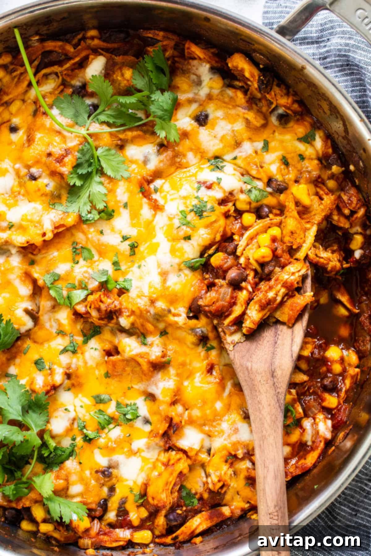 Mexican chicken enchilada in a pan with a wooden spoon, showcasing a vibrant and delicious dish.