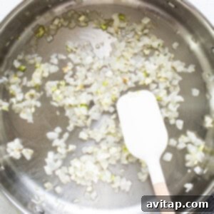 Sauteing onions in a pan with a wooden spatula.
