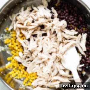 Easy One-Pan Chicken Enchiladas 11 Chicken, black beans, and corn being mixed in a pan with a wooden spoon.