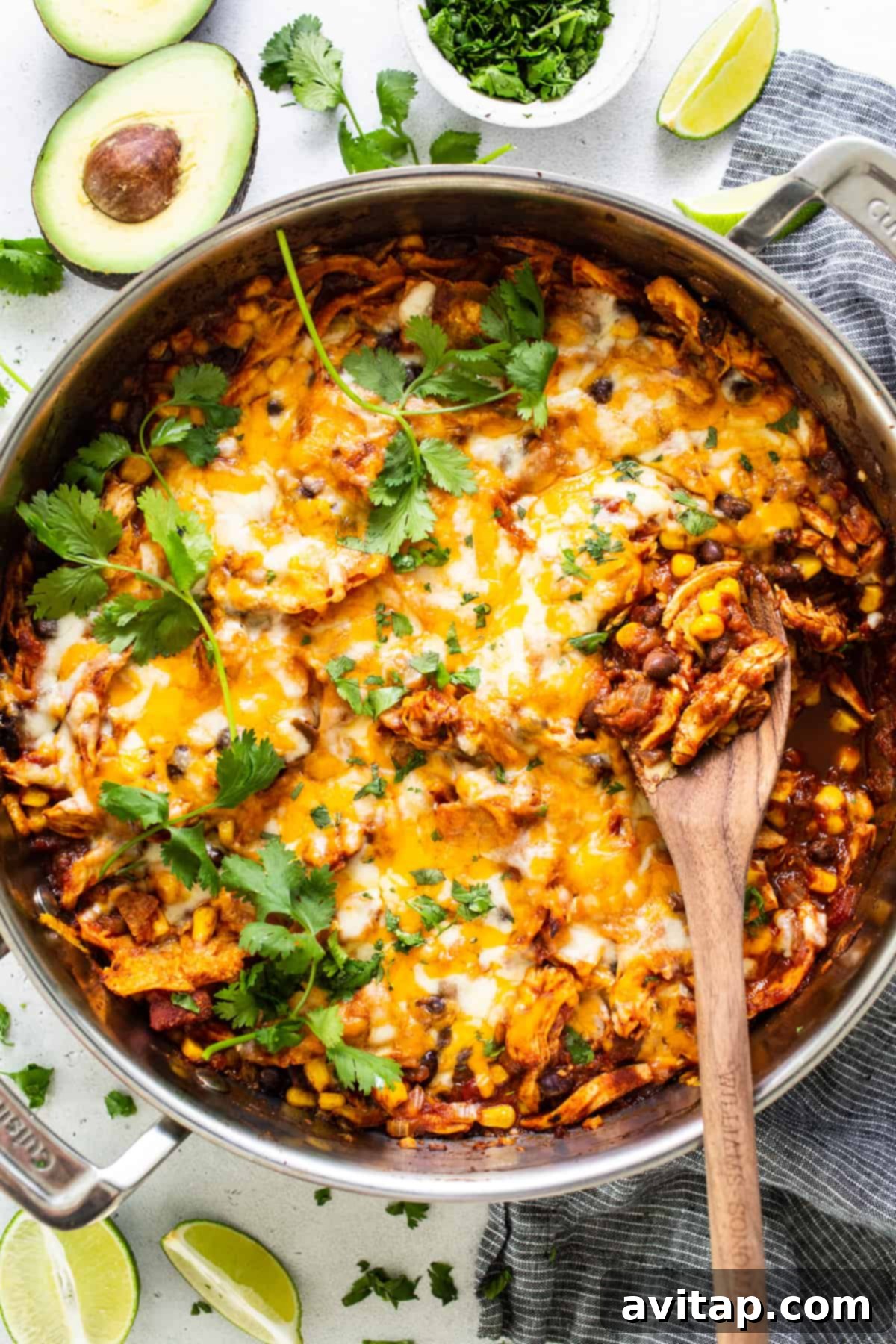 A close-up of the Mexican chicken enchilada in a pan with a wooden spoon, showing its rich texture.