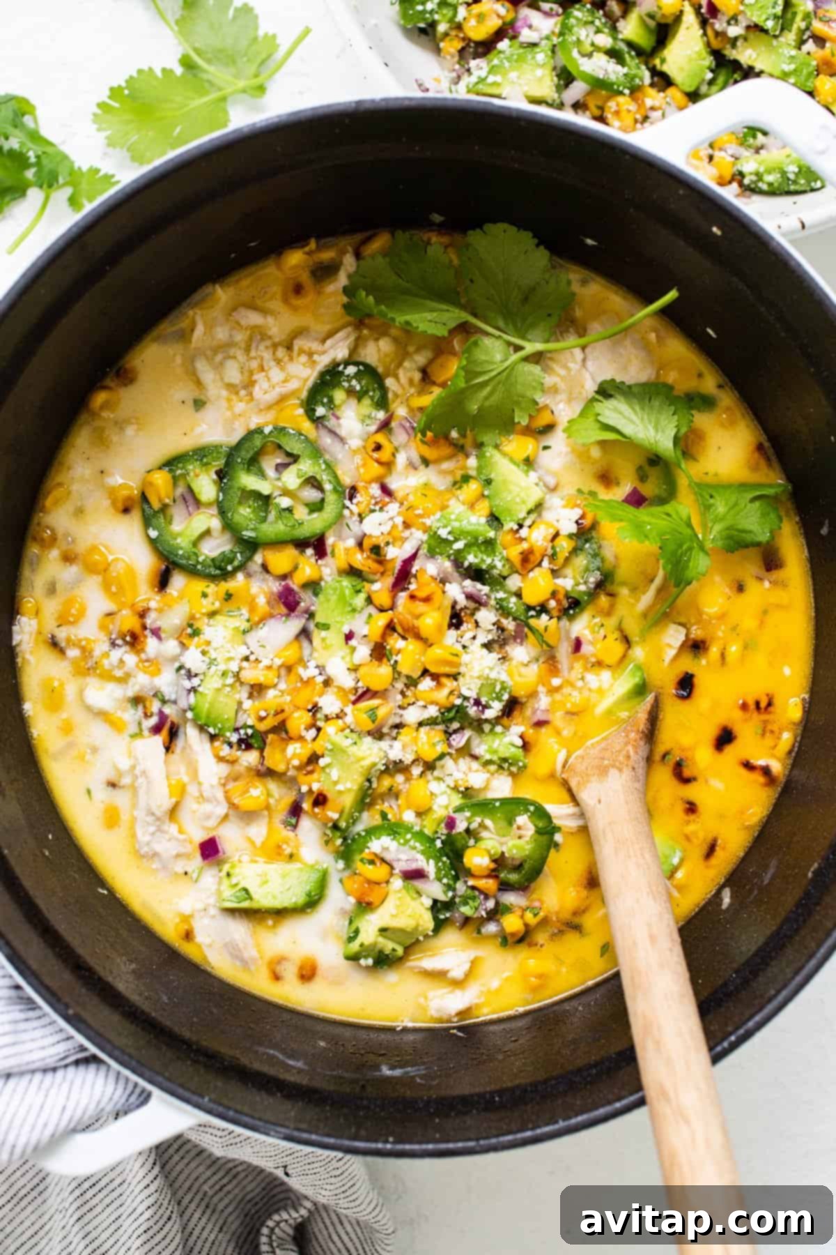 An overhead shot showcasing simmering chicken, corn, and other vibrant vegetables in a large pot, with steam gently rising, highlighting the inviting textures of the ingredients within the chili.