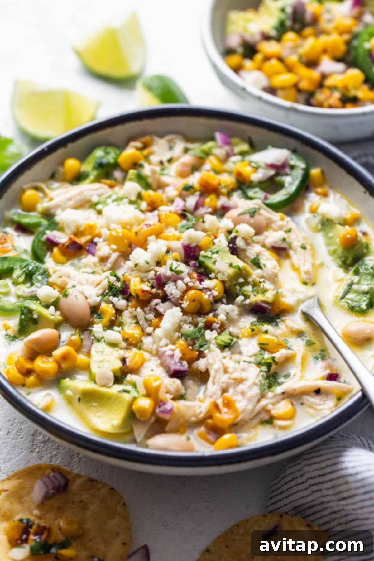 A visually appealing close-up shot of a steaming bowl of Street Corn Chicken Chili, generously garnished with fresh herbs and a vibrant mix of toppings, beautifully accompanied by a side of perfectly crispy tortilla chips, highlighting its comforting and delicious appeal.
