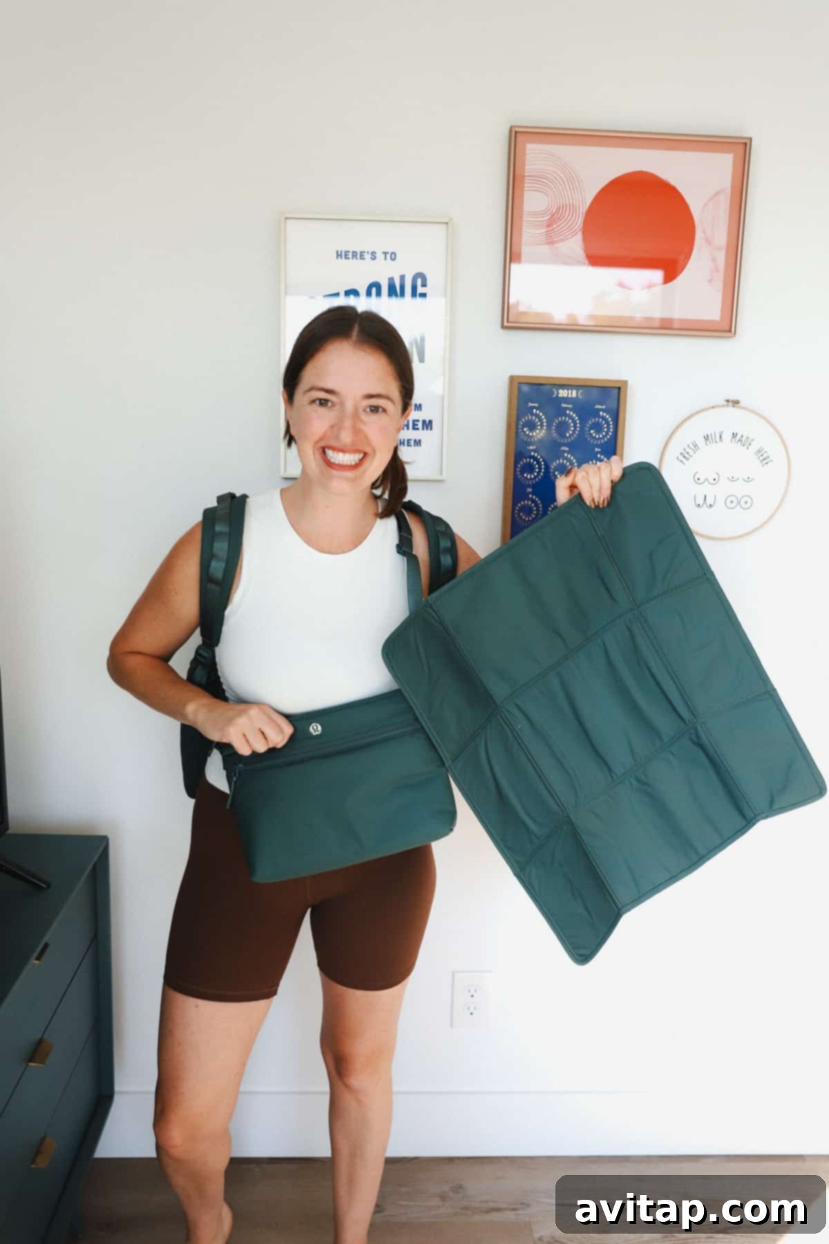 A woman in casual attire holding the emerald green Lululemon New Parent Backpack with a relaxed posture, demonstrating its everyday wearability and aesthetic appeal.