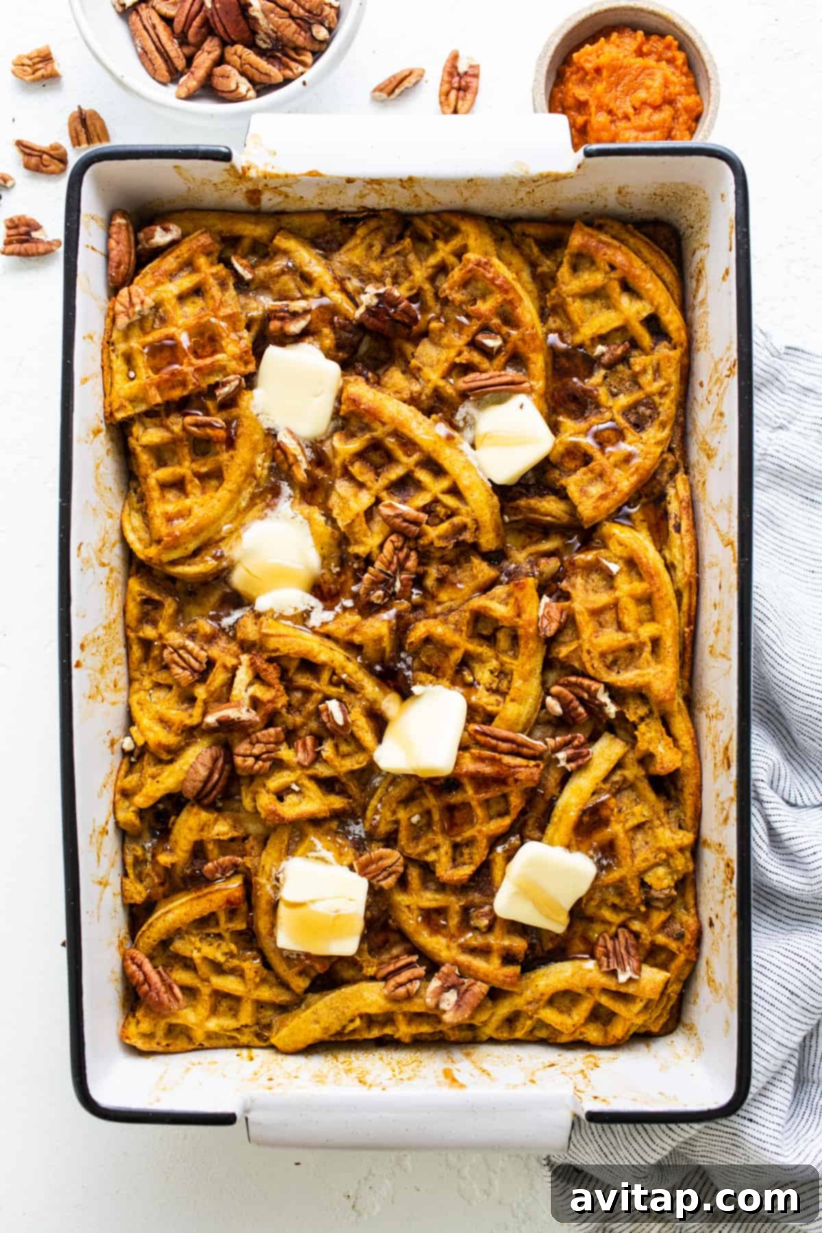 Delicious Pumpkin Waffle Casserole in a baking dish, garnished with butter and pecans.