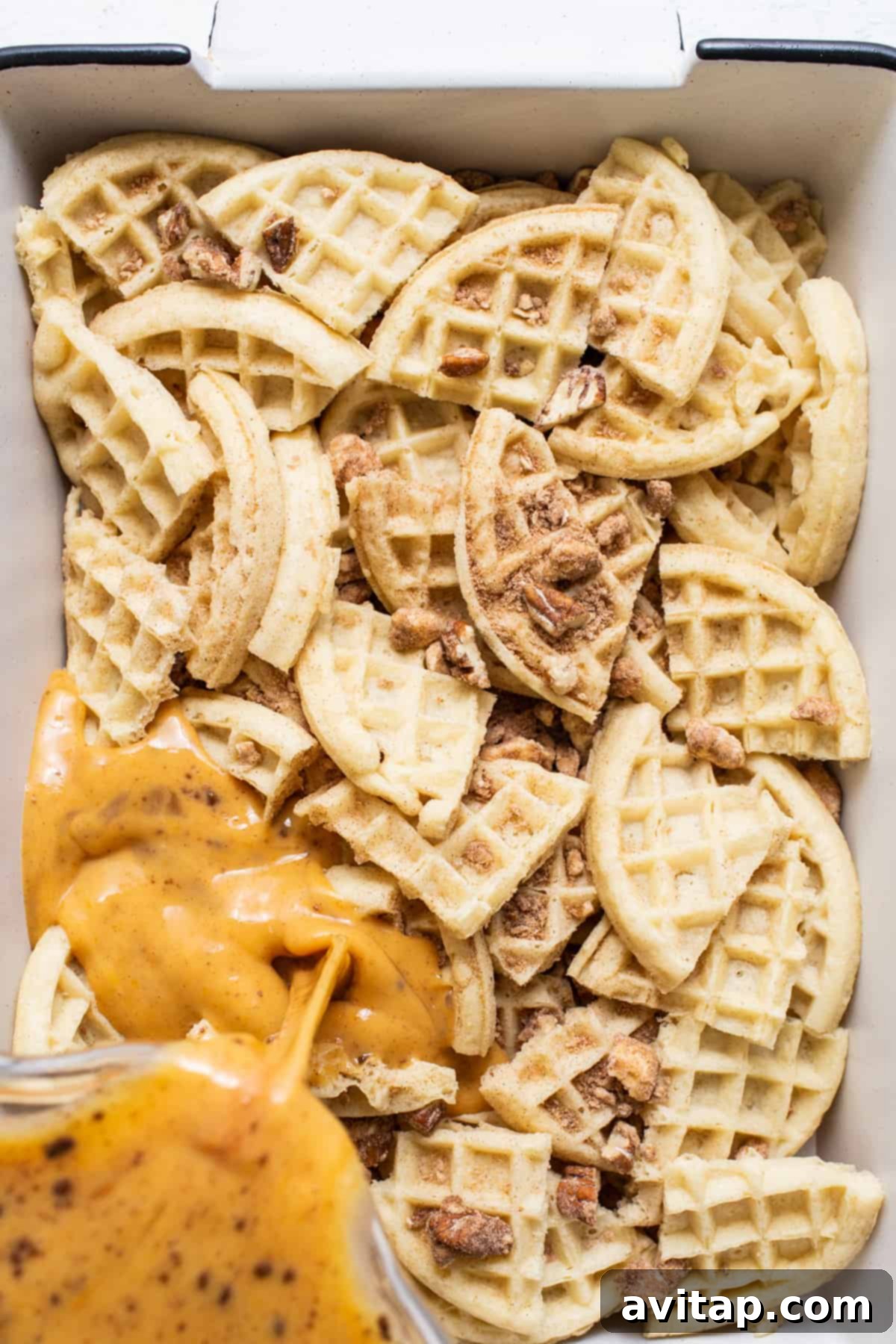 Baked waffles in a white baking dish, drenched in a rich sauce, ready for serving.