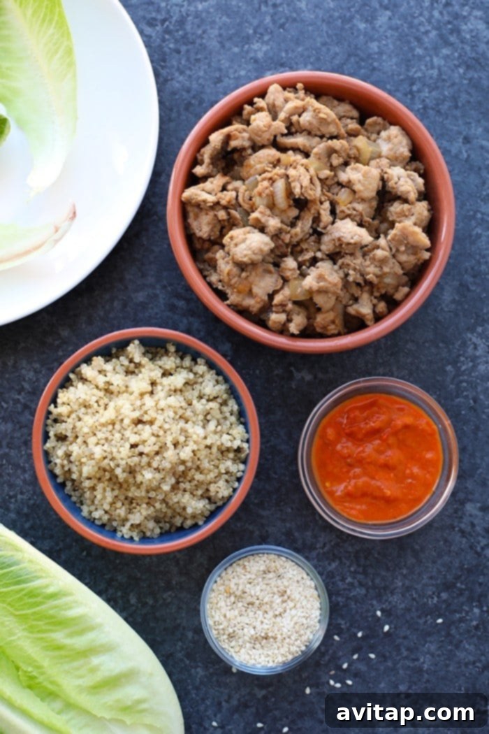 Korean Chicken Lettuce Wraps Ingredients Bowls containing ingredients for Korean chicken lettuce wraps: quinoa, seasoned ground chicken, Gochujang, and sesame seeds.