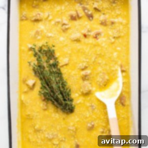 A casserole dish with the mixed ingredients and a sprig of fresh thyme submerged in the center of the liquid.