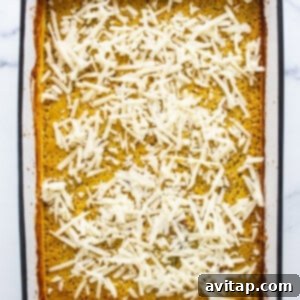 A white baking dish with a layer of melted, golden-brown cheese on top of the casserole.