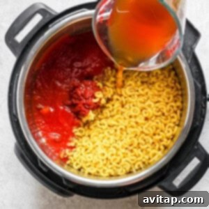 A person pouring sauce into a pot of pasta.