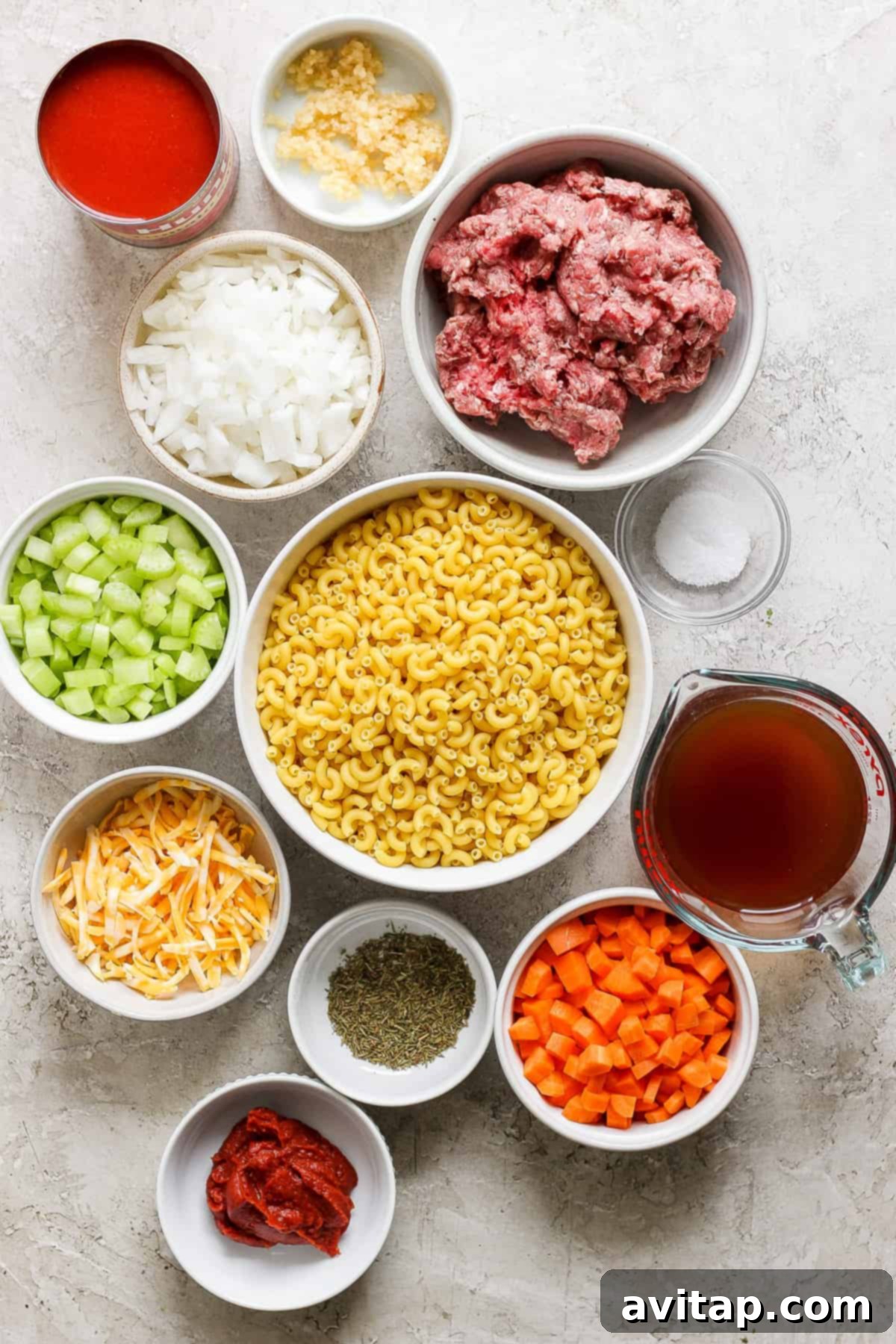 Ingredients for meatballs in white bowls on a white background.