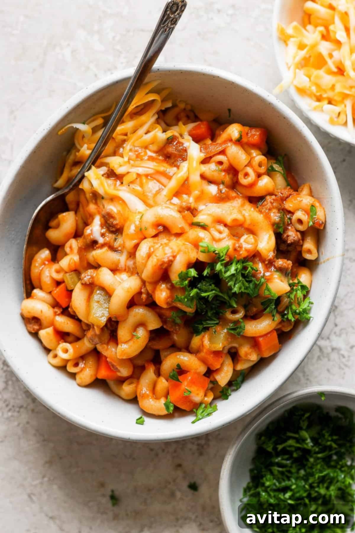 A bowl of macaroni and cheese with carrots and parsley.