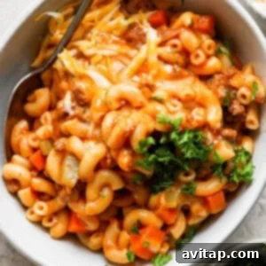 A bowl of macaroni and cheese with meat and vegetables.