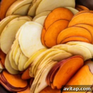 A bowl full of uniformly thin and perfectly prepared sweet potato slices.