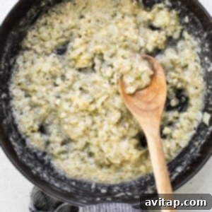 A frying pan on a stovetop with sautéing onions and garlic, and a wooden spoon, creating the aromatic base for the sauce.