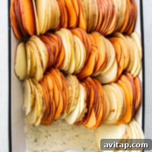 Thinly sliced sweet potatoes meticulously arranged in a baking dish, ready for the cheese sauce.