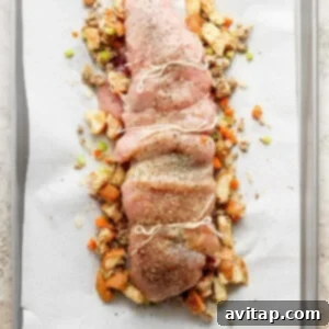 A baking sheet with a tied turkey roulade placed on a bed of extra stuffing, ready for the oven.