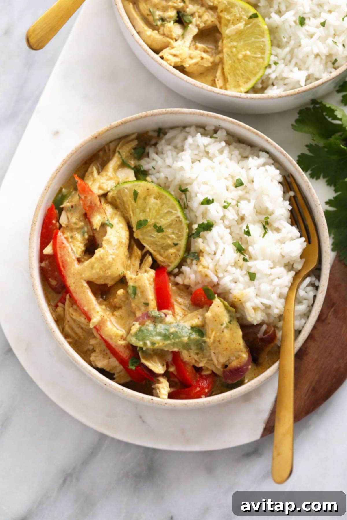 Aromatic Coconut Curry Chicken 2 Coconut curry chicken served in a bowl with rice, bell peppers, and fresh cilantro garnish, showcasing its rich texture.